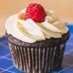 close up of chocolate cupcake topped with raspberry