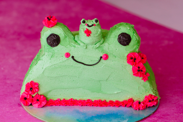 green buttercream frosted frog cake with derpy smile