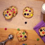 smartie cookies on table next to glass of milk
