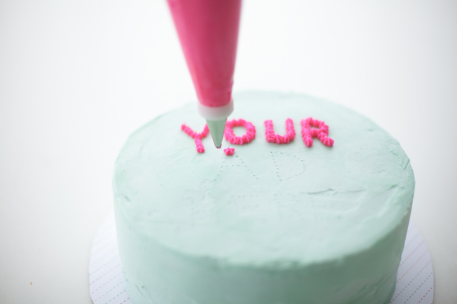 piping letters onto a cake